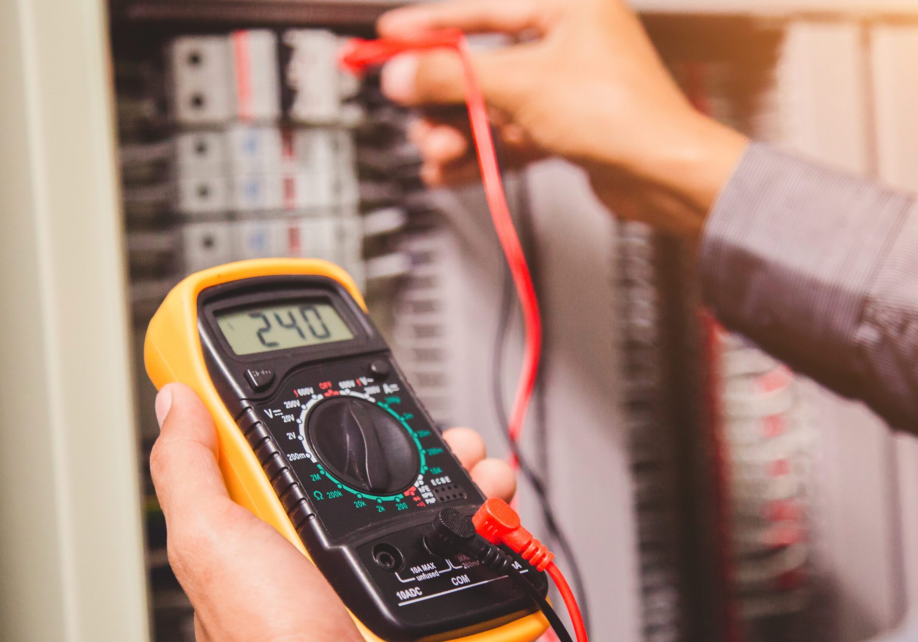 Engineer is measuring voltage or current by voltmeter in control panel